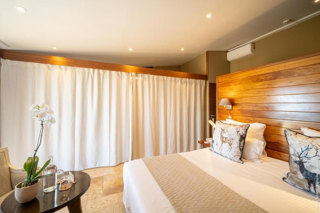 Chambre élégante avec tête de lit en bois et oreillers décoratifs à l'hôtel 5 étoiles Diana Dea Lodge Réunion